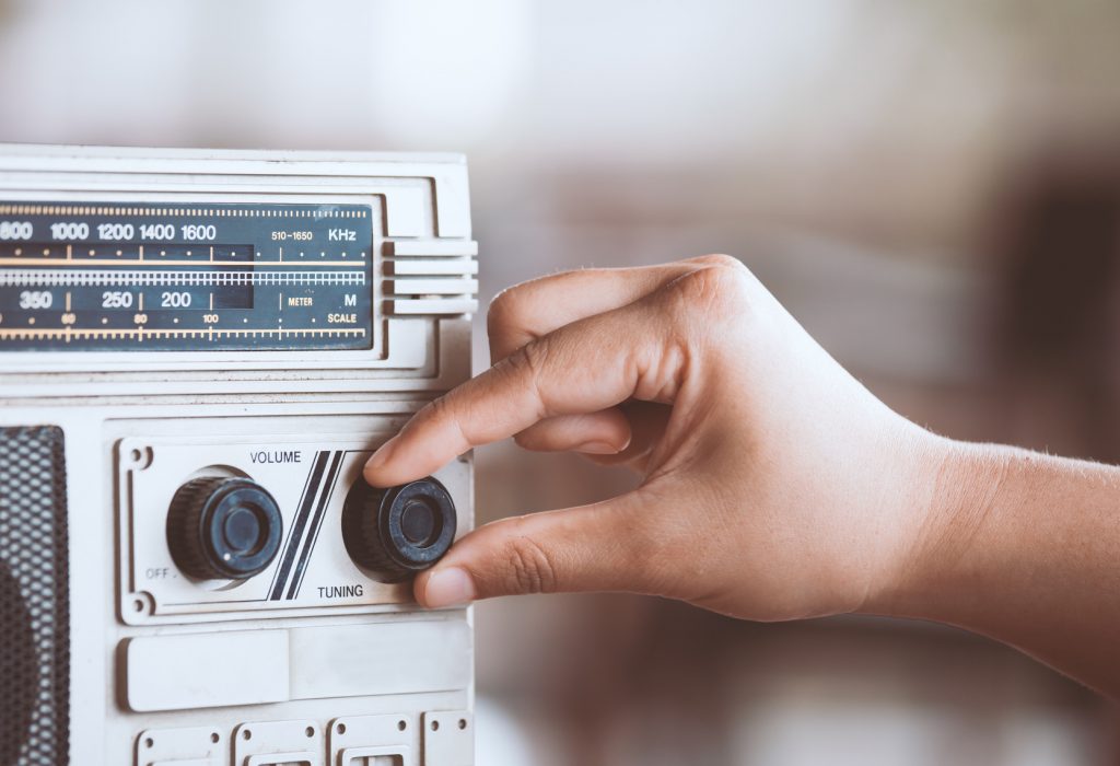 Woman hand adjusting the sound volume on retro radio cassette stereo in vintage color tone