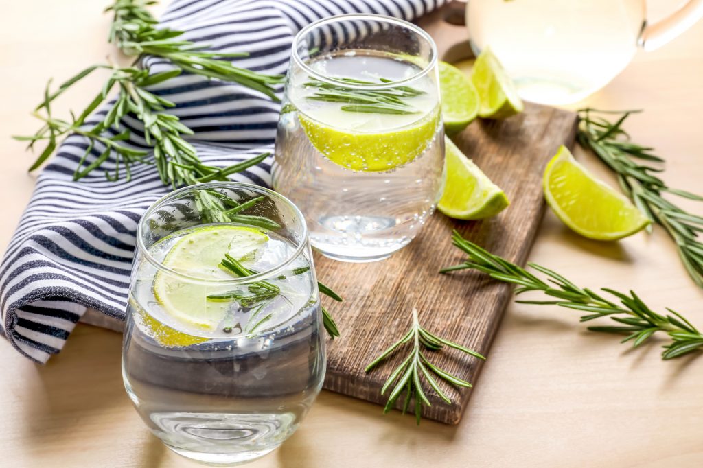 Glasses of fresh lime lemonade with rosemary on table