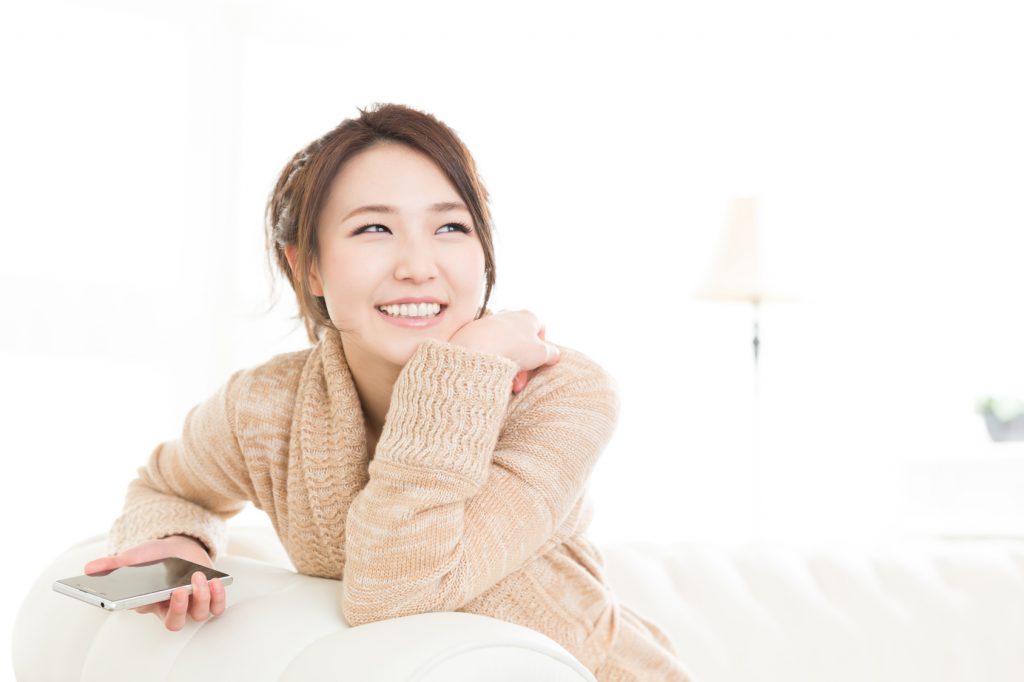 部屋でスマートフォンを見る女性