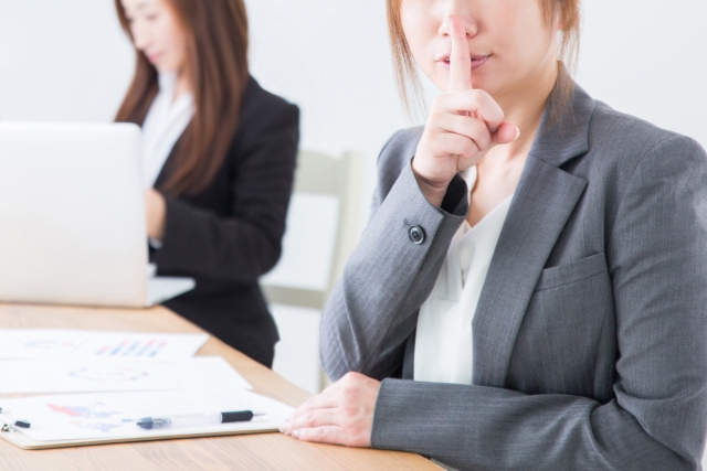 「お静かに」というジェスチャーをする女性