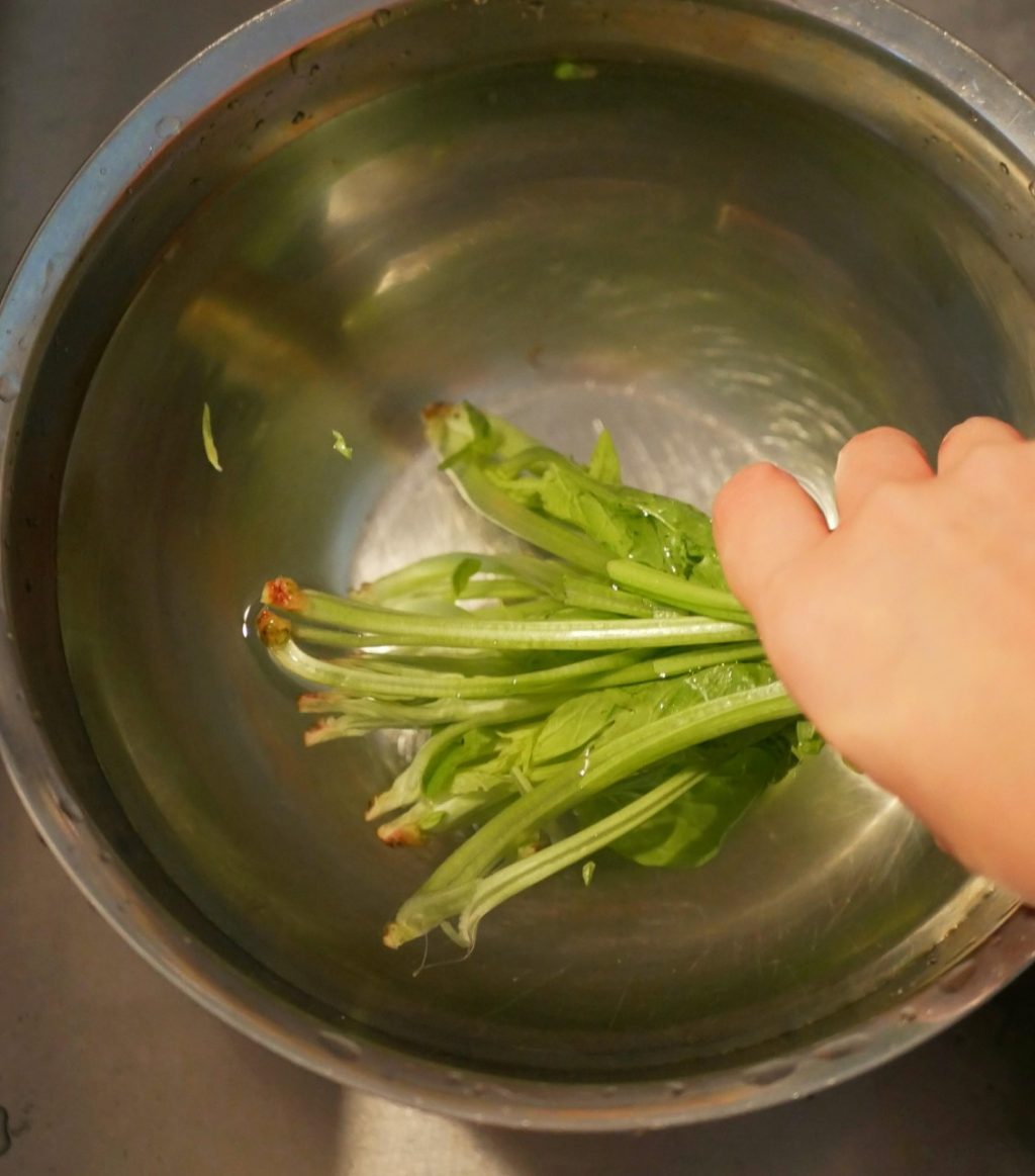 ほうれん草は茎に十字に切り込みを入れて、水を張ったボウルに入れて、しっかりと洗う