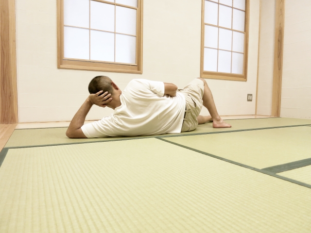 畳で横になる男性