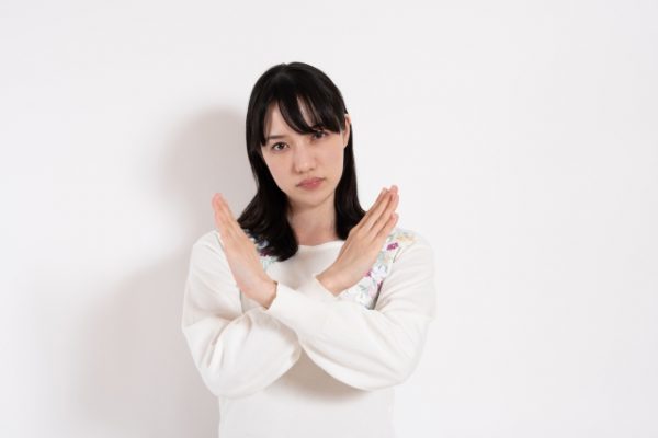 手でバツ印を作る女性