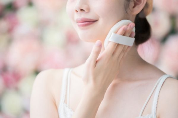 パフで粉をつける女性
