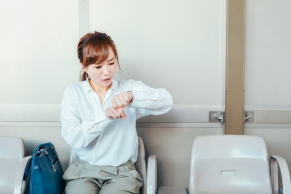 駅で時間を確認する女性