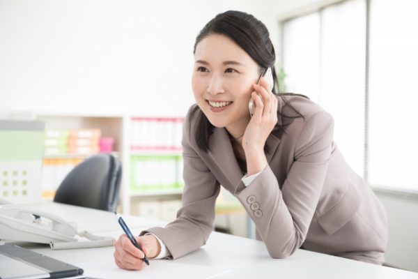 電話をしながらメモを取る女性