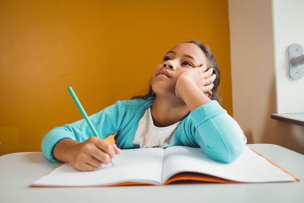 ノートに書くことを考えている女の子