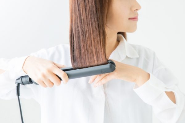 ヘアアイロンを使う女性