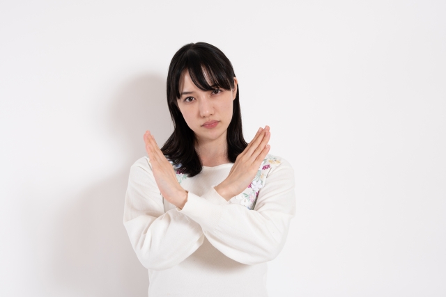 ばつ印のジェスチャーをする女性