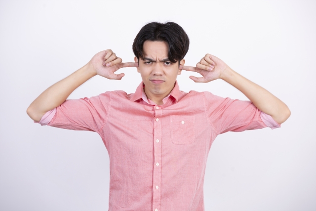 耳をふさぐ男性