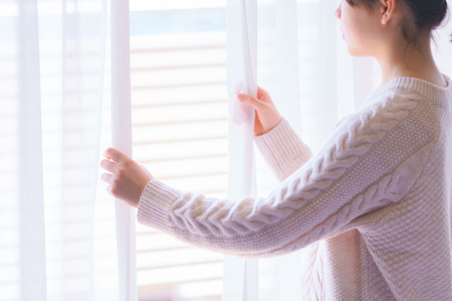 カーテンを開ける女性