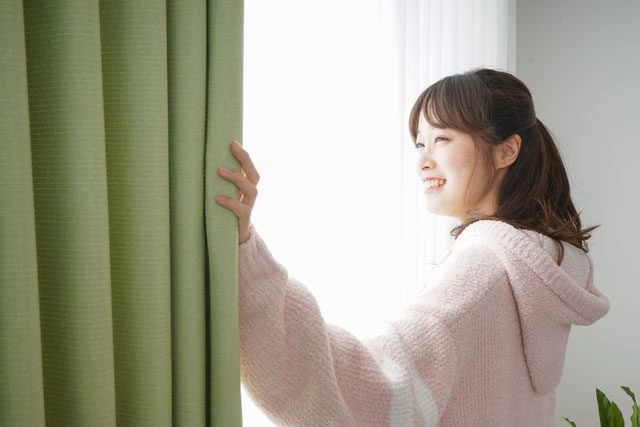 朝カーテンをあける女性