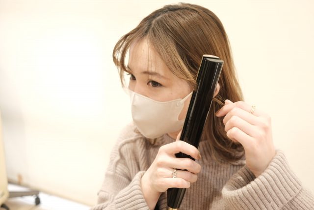 ヘアアイロンを使う女性