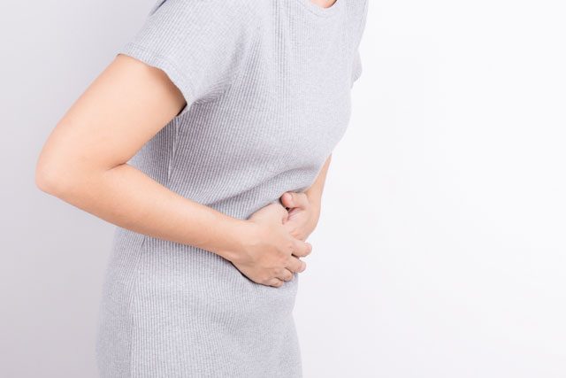 お腹をおさえる女性