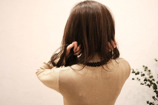 ヘアオイルをつける女性