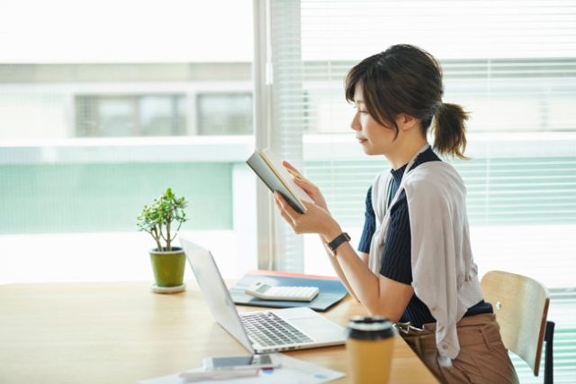 窓辺で本を手に勉強する女性