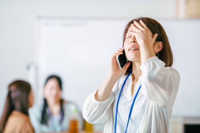 電話をしながら頭を抱える女性