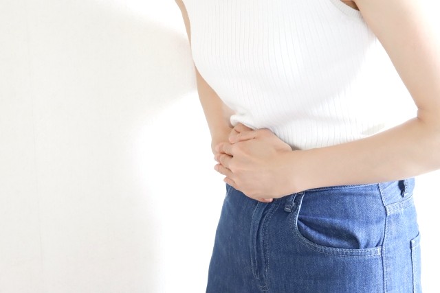 腹部を手で押さえる女性