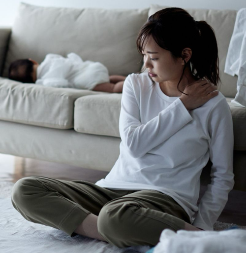 肩をおさえる女性