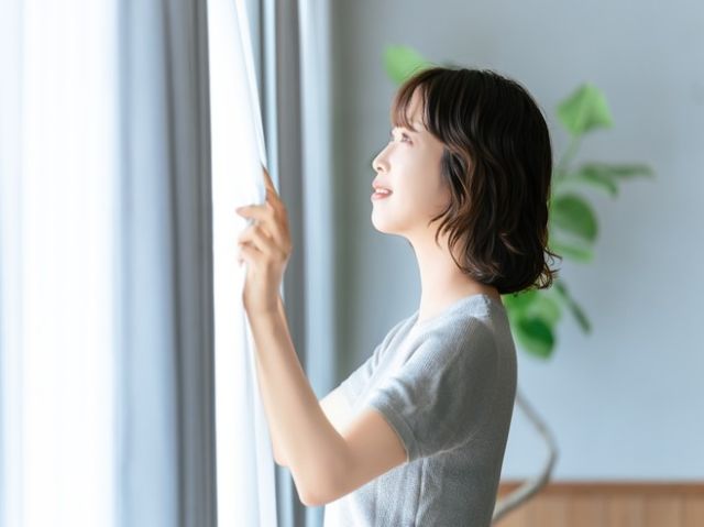 カーテンをあける女性
