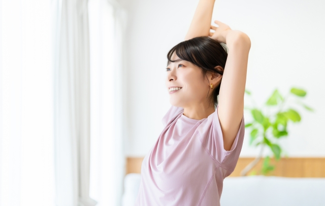 リビングで背伸びする女性