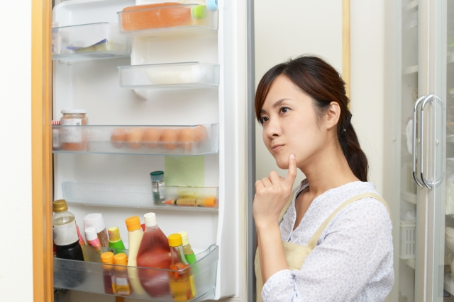 冷蔵庫前で悩む女性