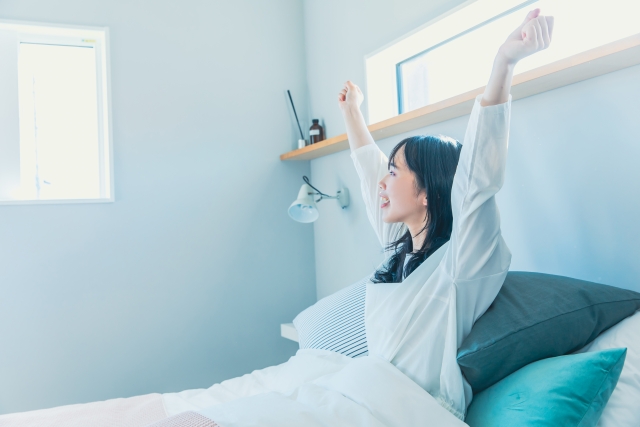 ベッドの上で伸びする女性