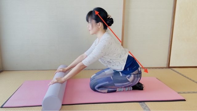 正座で両手をポールに置き、尾骨から頭までを斜め一直線に伸ばす女性