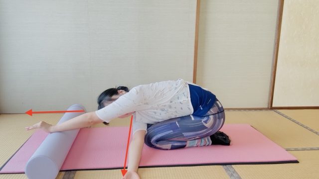 正座から上体を倒し、片腕を反対側の脇の下にくぐらせて胸郭をひねる女性